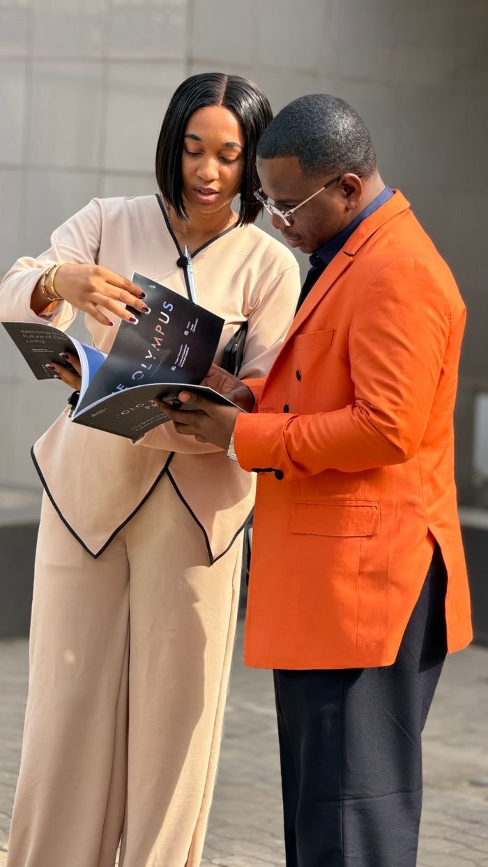 Services A man and woman in professional attire discussing a magazine outside on a sunny day.